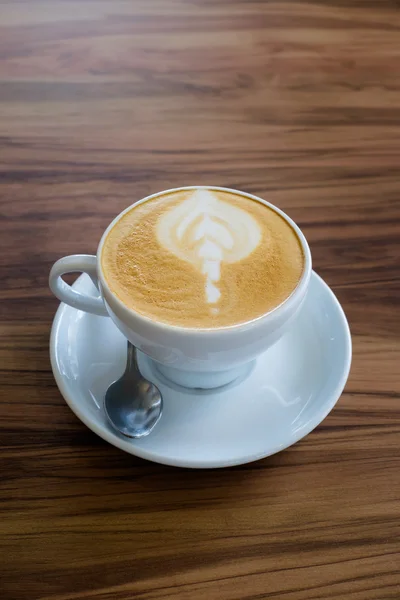 Ένα φλυτζάνι του latte art καφέ στο ξύλινο τραπέζι — Φωτογραφία Αρχείου