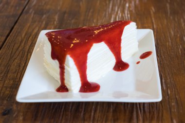 Ahşap masa üzerinde çilek soslu krep pasta