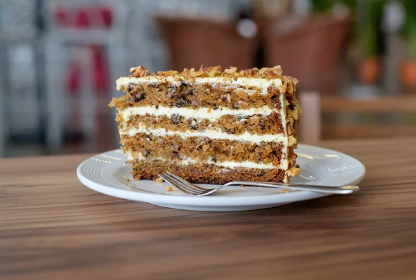 Ahşap masa üzerinde beyaz tabakta havuç pasta dilimlenmiş