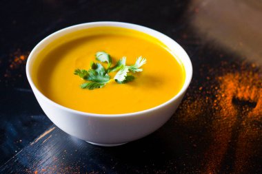 Restoranların masasındaki kasede sarı balkabağı kremalı çorba.,