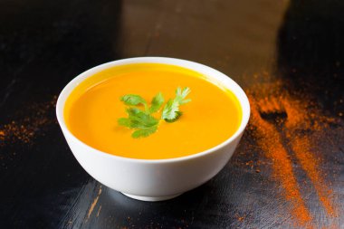 Restoranların masasındaki kasede sarı balkabağı kremalı çorba.,