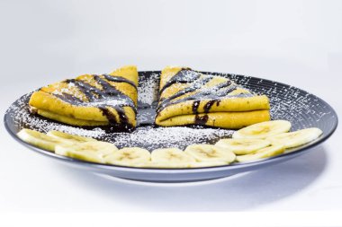 Tabağında muz olan çikolatalı krep, stüdyo çekimi.