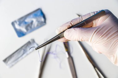 Ameliyat ekipmanları, neşter, bıçak, dikiş ve iğne beyaz arka planda. Doktorlar elleriyle dikiş atıyor..