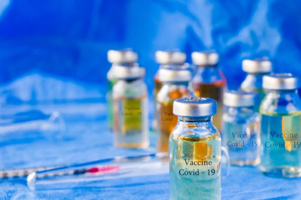 Corona virus and Covid - 19 new vaccine in ampules, different color variations of vaccine on the blue background