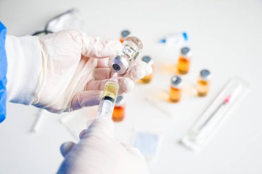 Corona virüsü ve Covid - 19 yeni aşı ampul ve şişe, iğne ve eldivenli doktorlar.