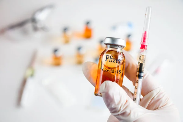 Tiflis, Georgia - 20 Kasım 2020: Pfizer Corona virüsü ve Covid - 19 yeni aşı ampul ve şişe, iğne ve eldivenli doktorlar.