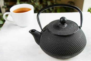 Bitki çayı, demir çaydanlık ve beyaz arka planda bir fincan çay, Çin geleneksel çayı.