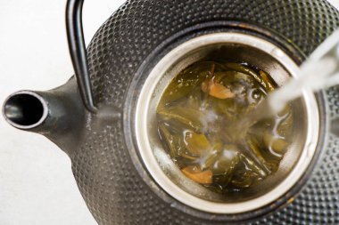 Bitki çayı, demir çaydanlık ve beyaz arka planda bir fincan çay, Çin geleneksel çayı.