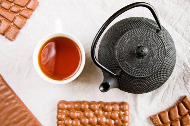 Beyaz arka planda çay, demir çaydanlık ve çikolata, sabah yemeği ve içeceği.