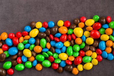 Gri arka planda çikolata şekeri, renkli şeker dokusu, yakın plan ve makro