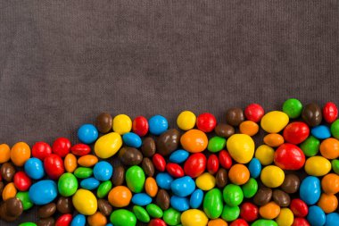 Gri arka planda çikolata şekeri, renkli şeker dokusu, yakın plan ve makro