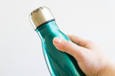 Termos mavi su şişesi ve beyaz arka planda insan eli.