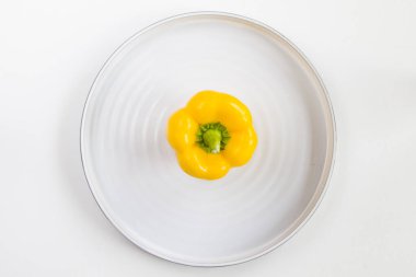 Tabakta sarı dolma biber, beyaz arka plan ve yüksek açı, renkli sebzeler.