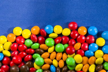 Mavi arkaplanda M & M 'nin şekeri, renkli şeker ve çok renkli gradyan