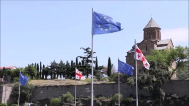 Mavi gökyüzünde Avrupa Birliği bayrağının, yıldızların ve mavi rengin videosu. Rüzgarda hareket eden bayrağın yakın çekimi, Tiflis, Georgia 'da rüzgarlı hava.