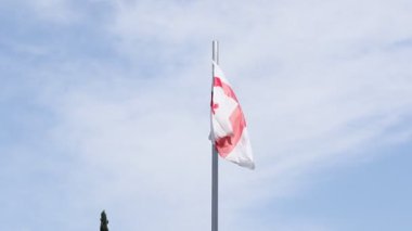 Gökyüzünde rüzgarda dalgalanan Gürcistan bayrağı.