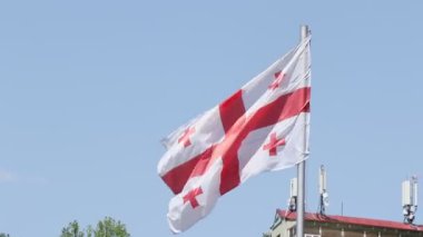 Gökyüzünde rüzgarda dalgalanan Gürcistan bayrağı.