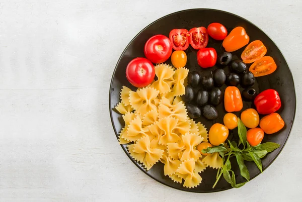 Pasta Ingrediënten Rauwe Pasta Kerstomaten Olijven Basilicum Bladeren Zwarte Plaat — Stockfoto