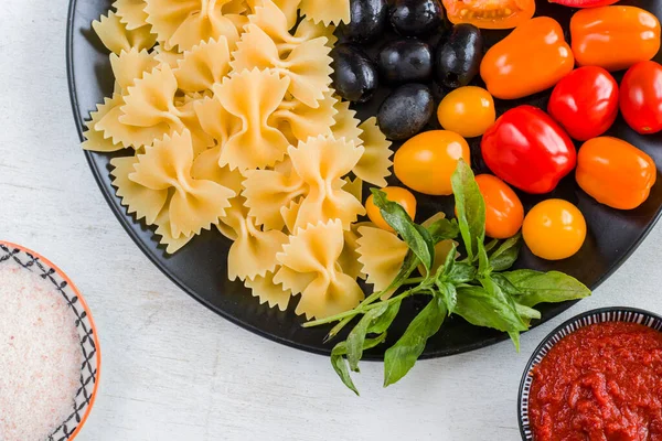 Pasta Ingrediënten Rauwe Pasta Kerstomaten Olijven Basilicum Bladeren Zwarte Plaat — Stockfoto