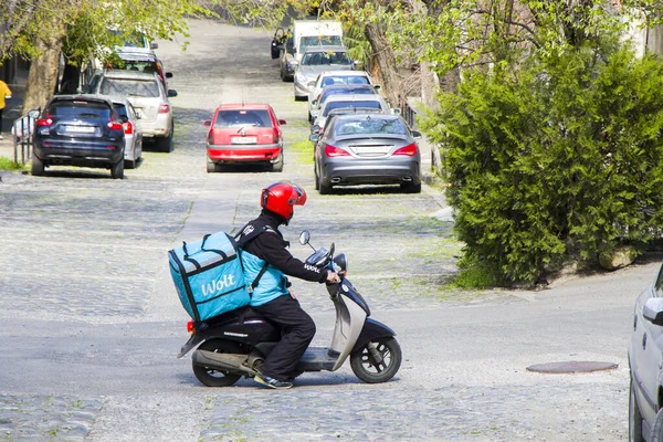 Tiflis, Gürcistan - 15 Nisan 2021: Scooter ve kutulu Wolt teslimat kuryesi