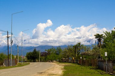 Gürcistan 'daki boş otoyol ve yol güneş ışığı, mavi gökyüzü ve ağaçlar boyunca