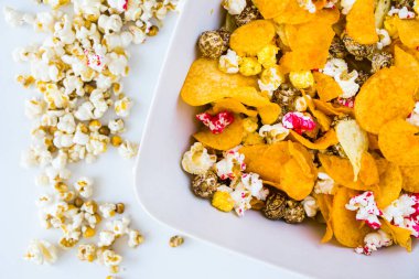 Beyaz arka planda tuzlu ve tatlı patlamış mısır ve cips, düşük açı