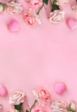 Çiçeklerden oluşan bir çerçeve pembe güller pembe kağıtta arkaplanlarında yazı için yer olan kalpler. Sevgililer Günü 'nün dekorasyonu. Üst manzara, düz uzanma