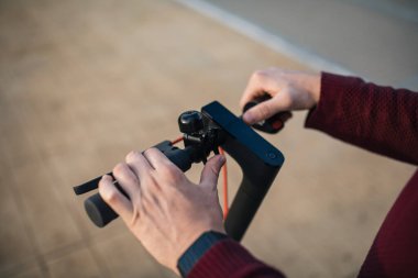 Elleri düğmelere değen elektrikli paten. Şehirde dolaşmak için elektrikli paten kullanan genç bir adam..