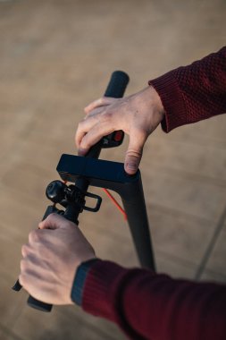 Elleri düğmelere değen elektrikli paten. Şehirde dolaşmak için elektrikli paten kullanan genç bir adam..