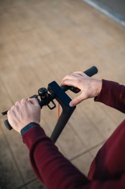 Elleri düğmelere değen elektrikli paten. Şehirde dolaşmak için elektrikli paten kullanan genç bir adam..