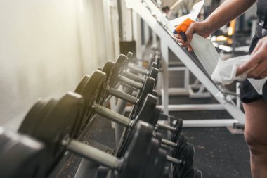 Spor salonunda ağırlık temizleyen bir adam. COVID-19. Sağlık ve spor kavramı.