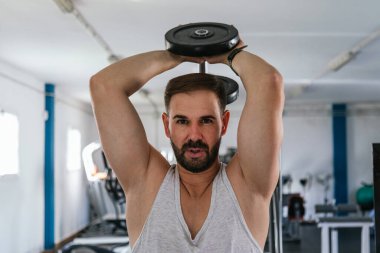 Sırtında dambıllarla triseps yapan bir adam..