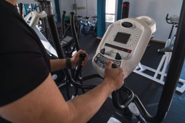 Tanımlanamayan adam spor kulübünde eliptik antrenör tırabzanları tutuyor. Koşu bandında çalışan kardiyo eğitimi geçmişi. Sağlıklı yaşam tarzı, spor salonunda erkek eğitimi..