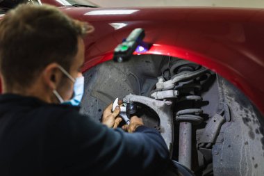 Tamirci araba süspansiyonunu tamir ediyor. Ellere odaklan. COVID 19