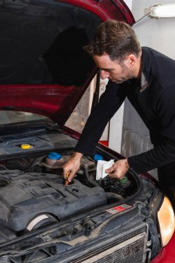 Tamirci arabanın motorundaki yağ seviyesine bakıyor. Otomobil mekaniği kavramı