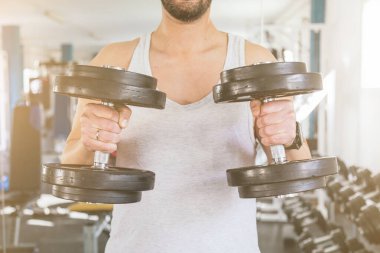 İki dambılı tutan bir adamın elleri, tanınmaz halde. Sağlık ve refah kavramı