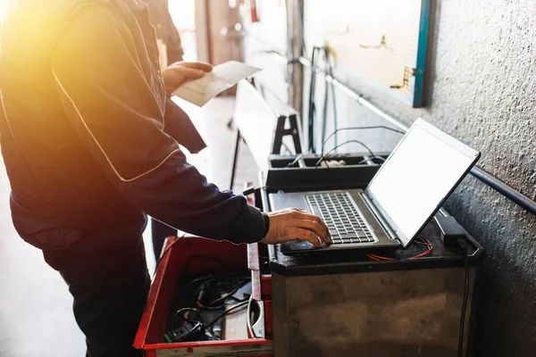 Mechanic diagnosing the car on a computer. Sunlight effect. Automotive concept.