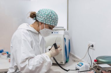 Masasında cerrahi maskeli ve takma dişleri olan bir diş teknisyeninin elleri. sağlık kavramı