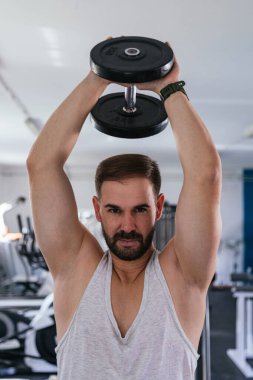 Sırtında dambıllarla triseps yapan bir adam..