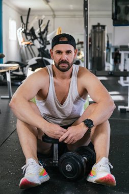 Salonda oturan genç adam, halterler dinleniyor..