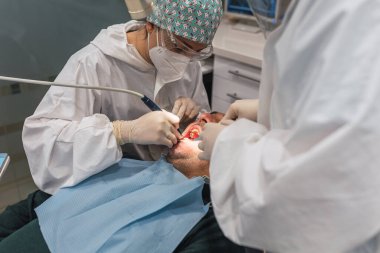 Ofisinde hastası olan bir kadın dişçi. Ağzı açık hasta ve dişçi kadın çalışıyor. diş sağlığı kavramı.