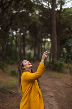 Güzel bir kadın sarı bir ceketle şapkasını havaya fırlatıyor. Gülümse. Özgürlük kavramı.