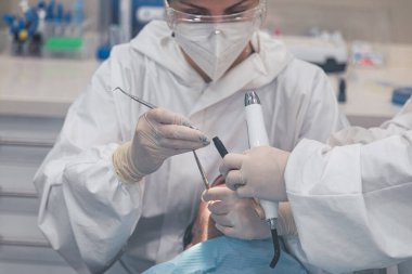 Ofisinde hastası olan bir kadın dişçi. Ağzı açık hasta ve dişçi kadın çalışıyor. diş sağlığı kavramı.