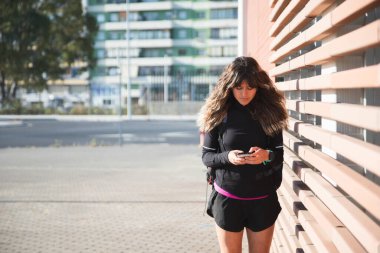 Açık havada egzersiz yaptıktan sonra telefonu kullanan tanınmamış sporcu kadın. Güzel kadın. Spor Konsepti