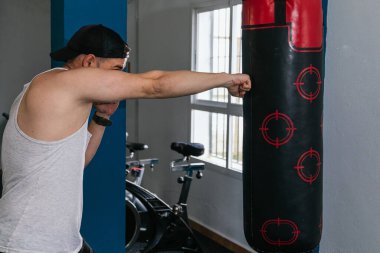 Spor salonunda kum torbası yumruklayan bir adam. Spor salonu.