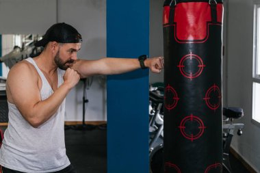 Spor salonunda kum torbası yumruklayan bir adam. Spor salonu.