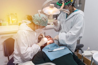 Ofisinde hastası olan bir kadın dişçi. Ağzı açık hasta ve dişçi kadın çalışıyor. diş sağlığı kavramı.