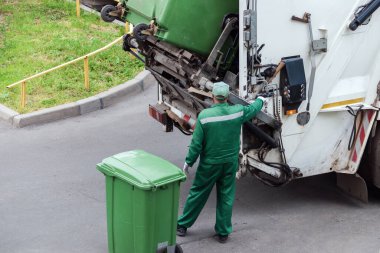 Çöp toplayıcısı çöp kamyonunu çöp tenekelerinin atıklarıyla dolduruyor.