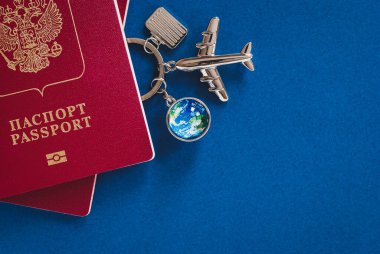 Russian passport for international travel, airplane, globe and luggage models on blue background with copy space clipart