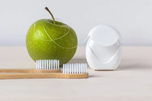 Bamboo toothbrushes, green apple and dental floss on white background - dental care routine to keep healthy teeth